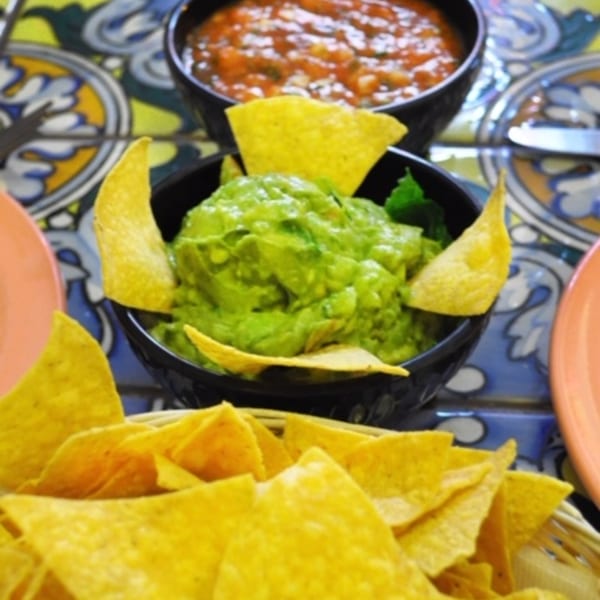Guacamole and salsa with tortilla chips on a colorful tiled table at Sol Azteca.