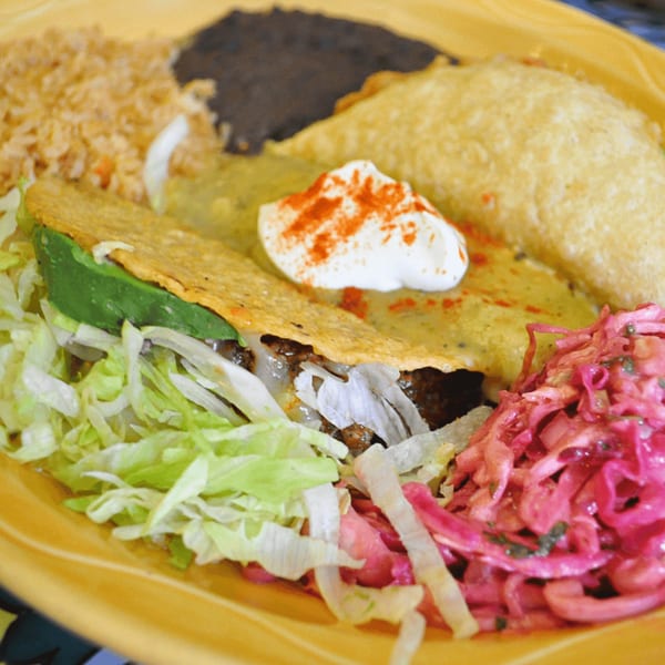 A Sol Azteca Mexican combo plate with a taco, enchilada, rice, black beans, and pickled cabbage.