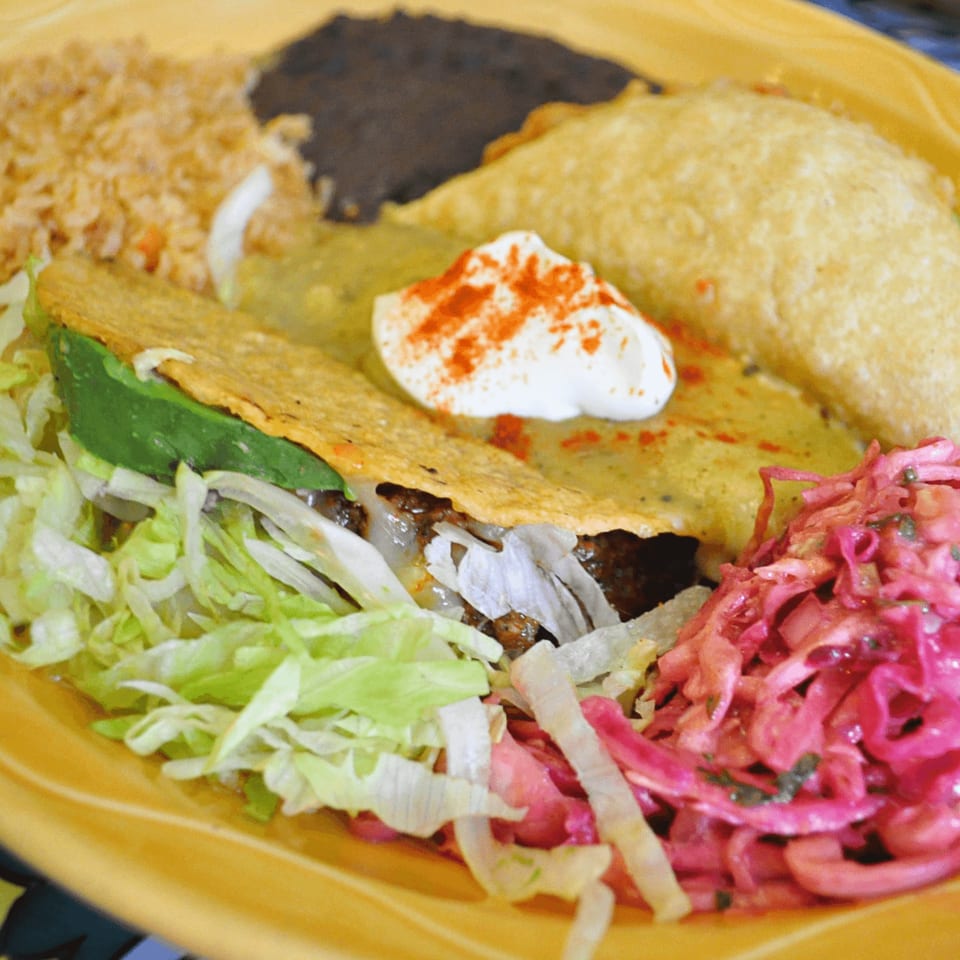 A Sol Azteca Mexican combo plate with a taco, enchilada, rice, black beans, and pickled cabbage.